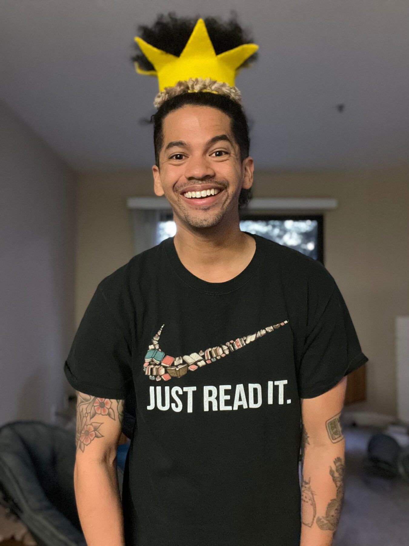 Mr. Mychal in a yellow crown and a black t-shirt that says: Just Read It
