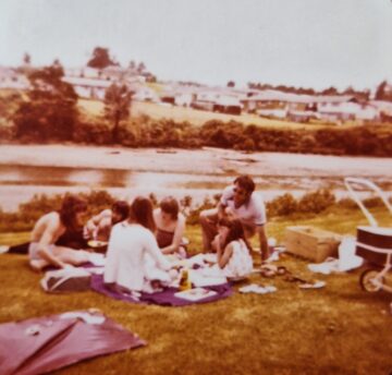 A small family group having a picnic on the banks of a creek. 